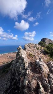 The edge of a rocky ridge with the sea visible behind it